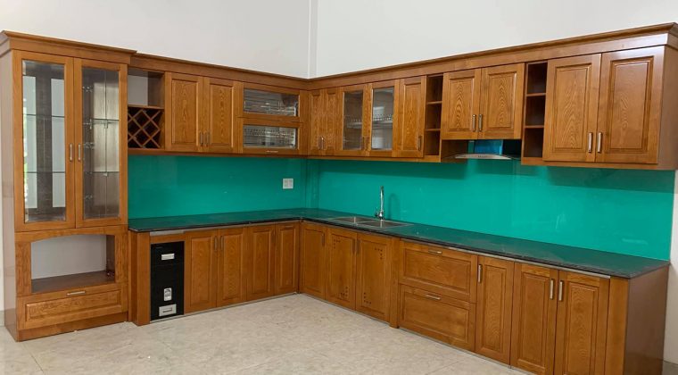 Tủ bếp gỗ sồi Nga dáng chữ L với kính bếp màu xanh ngọc hiện đại