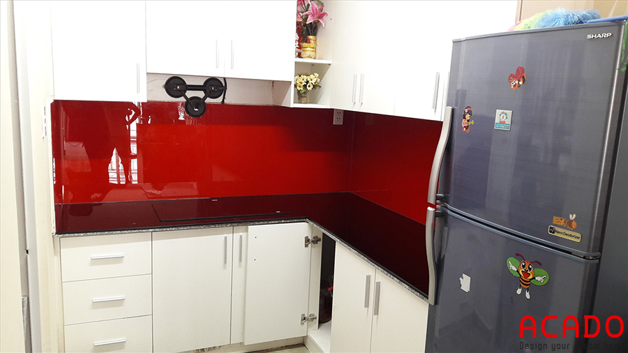 Tủ bếp trắng kết hợp kính bếp màu đỏ nổi bật, thu hút.