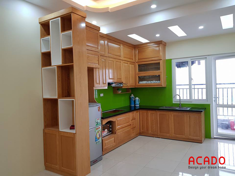 Tủ bếp gỗ tự nhiên màu vàng kết hợp kính bếp xanh lá cây nổi bật, thu hút.