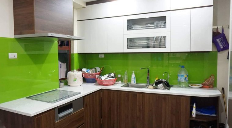 Tủ bếp Melamine trắng kết hợp màu vân gỗ ấm cúng, hiện đại kính bếp màu xanh làm điểm nhấn