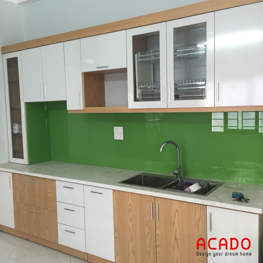 Tủ bếp Laminate màu trắng kết hợp màu vân gỗ , kính ốp bếp màu xanh lá cây mát mẻ, thu hút.